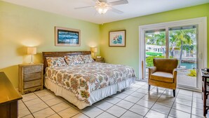 A bedroom with a bed, a chair, a nightstand, and a ceiling fan. - Waterfront, Single-Story Home on a Canal w/ Dock, Kayaks, AC - 1 Small Dog OK (Key West)