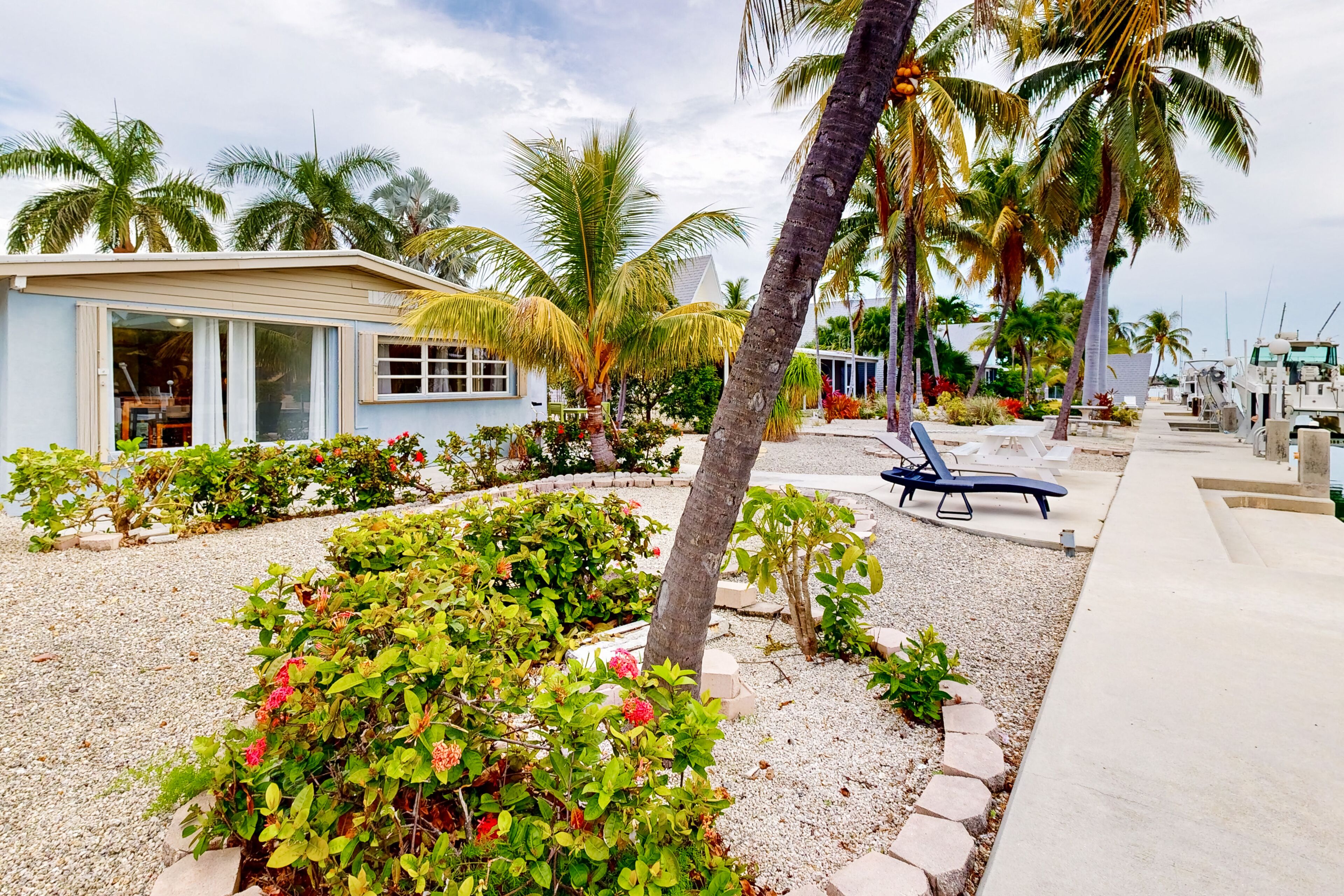 A beachfront property with a small building, palm trees, and a garden area.