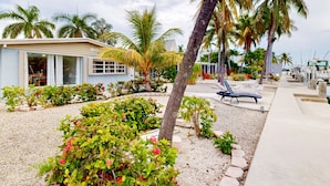 A beachfront property with a small building, palm trees, and a garden area. - Waterfront home with 60-ft dock, pool, & cabana club access - dog-friendly (Key Colony Beach)