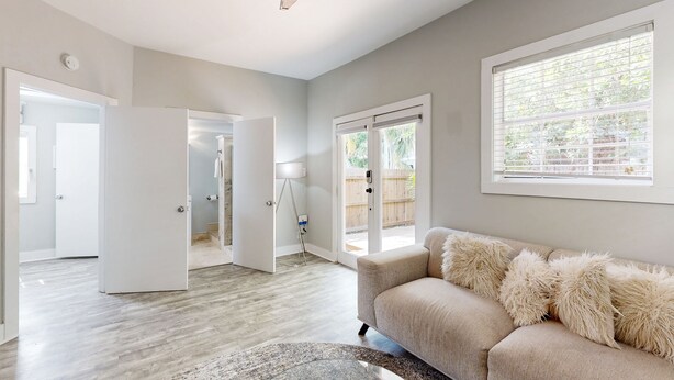A modern living room with a beige sofa, a glass coffee table, and a ceiling fan. - Centrally located cottage apartment with patio - walk to beach & dining (Key West)