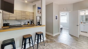 A modern kitchen with a wooden countertop, bar stools, and a flat-screen TV. - Centrally located cottage apartment with patio - walk to beach & dining (Key West)
