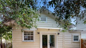 A single-story house with a front door, a small window, and a covered patio area. - Centrally located cottage apartment with patio - walk to beach & dining (Key West)
