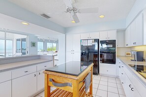 A modern kitchen with white cabinetry, a black countertop, and a ceiling fan. - Luxurious waterfront home with panoramic views, pool, spa, & dock (Marathon)