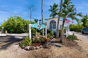 A sign for Ocean Point with a white building and palm trees in the foreground. - Breezy condo on the water with pool, hot tub & tennis court (Tavernier)