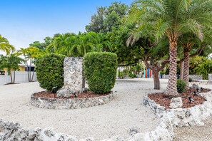 A landscaped garden with palm trees, neatly trimmed bushes, and a stone pathway. - Waterfront home with dock, pool table & private pool - walk to Sombrero Beach (Marathon)