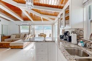 A modern kitchen with white cabinetry, a granite countertop, and a stainless steel sink. - Summerland Canal-Front Escape w/ Plunge Pool, Dock, Tiki Bar, WiFi & Laundry (Summerland Key)