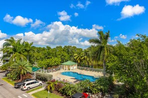 A swimming pool with a green roof, surrounded by palm trees and a small building. - Resort suite with pool, hot tub, tennis & full kitchen (Key West)