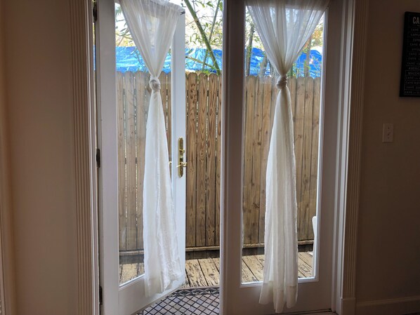 Uma porta com cortinas brancas e uma cerca de madeira na parte externa.