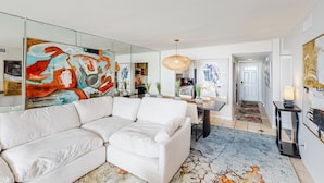 Ein modernes Wohnzimmer mit einem weißen Sofa, einem Essbereich und einer Küche im Hintergrund.