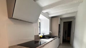 A modern kitchen with a central island, light wood flooring, and a minimalist design.