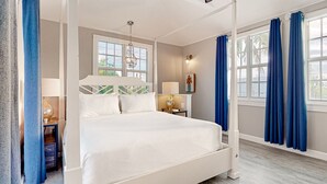 Quarto com uma cama grande, mesa de cabeceira, abajur e vista para o exterior pela janela.