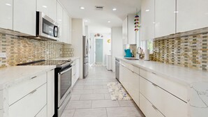 Een moderne keuken met witte kastjes, een magnetron en een backsplash met een patroon.