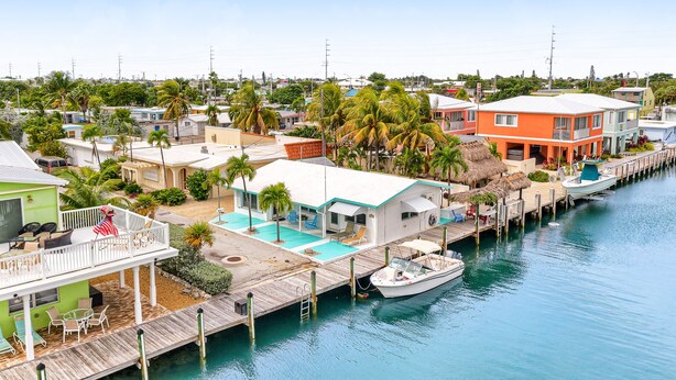 Um imóvel à beira-mar com um cais, piscina e barco.