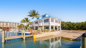 Ein Hotel am Wasser mit einer Anlegestelle, Booten und einer Palme.