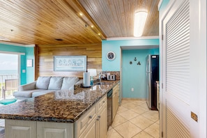 A kitchen with a granite countertop, wooden ceiling, and a light blue wall. - Updated ocean-view condo with 2 balconies, pool, hot tub, W/D, & AC (Tavernier)