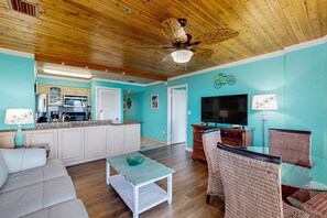 A living room with a sofa, a glass coffee table, wicker chairs, a TV, and a ceiling fan. - Updated ocean-view condo with 2 balconies, pool, hot tub, W/D, & AC (Tavernier)