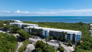 A multi-story hotel with a parking lot and a view of the ocean. - Updated ocean-view condo with 2 balconies, pool, hot tub, W/D, & AC (Tavernier)