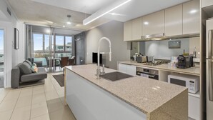 A modern kitchen with a central island, stainless steel appliances, and a view to the outside.