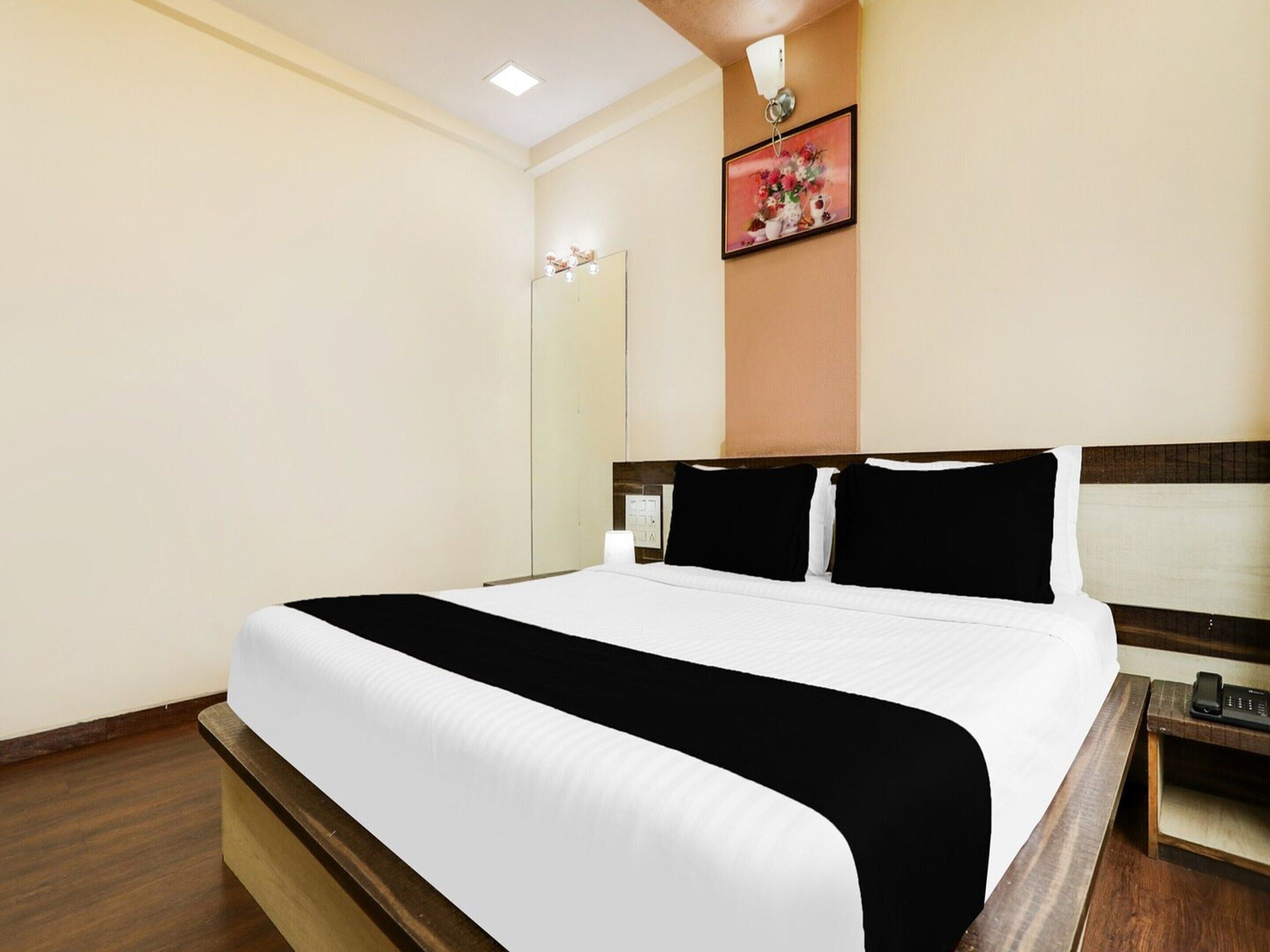 Une chambre d’hôtel avec un grand lit, une table de chevet avec un téléphone et un luminaire fixé au mur.