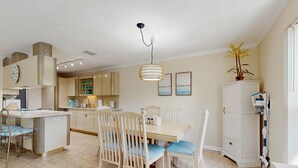A modern kitchen with a dining area, featuring a central island, wooden chairs, and a hanging light fixture. - Oceanside condo with heated pool, tennis courts & great location (Marathon)