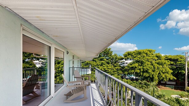 A balcony with a white ceiling, glass doors, and a view of a green landscape. - Oceanside condo with heated pool, tennis courts & great location (Marathon)