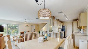A modern kitchen with a dining area, featuring a large table, chairs, and a hanging light fixture. - Oceanside condo with heated pool, tennis courts & great location (Marathon)