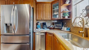 Une cuisine moderne dotée d’appareils électroménagers en acier inoxydable, d’armoires en bois et de plans de travail en granit.