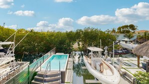 Un port de plaisance avec des bateaux amarrés, une piscine et une structure à toit de chaume.