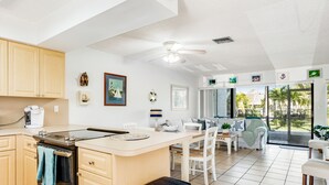 Une cuisine moderne dotée d’un îlot central, d’un coin repas offrant une vue agréable et d’un espace de vie agrémenté d’un ventilateur de plafond.
