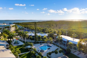 A resort with a swimming pool, palm trees, and a view of the ocean. - Spacious Townhome - Pool, Tennis & Marina - Central AC, WiFi & Snowbird-Friendly (Key Largo)