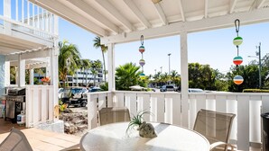Une terrasse extérieure couverte, avec une table ronde, des chaises et une décoration centrale de style tiki.