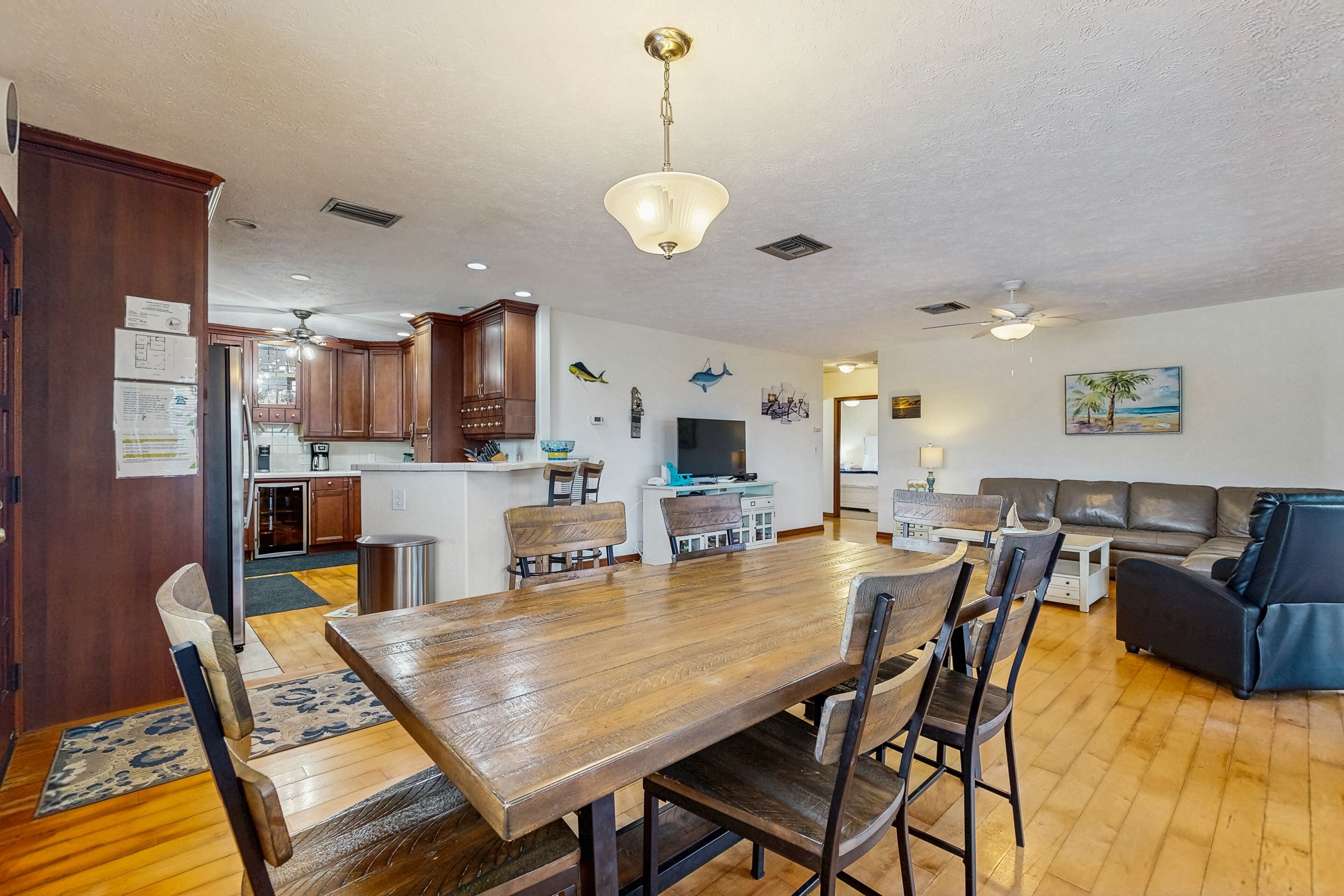Una cocina amplia con armarios de madera, una mesa de comedor con sillas y una sala de estar con sofá y televisor.