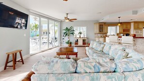 A spacious living room with a large sofa, a wooden coffee table, and a ceiling fan. - Oceanfront, Snowbird-Friendly Home with High-Speed WiFi, Ocean Views, and Dock (Key Largo)