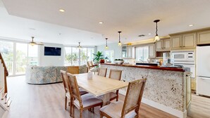 A spacious kitchen with a central island, wooden dining table, and chairs. - Oceanfront, Snowbird-Friendly Home with High-Speed WiFi, Ocean Views, and Dock (Key Largo)