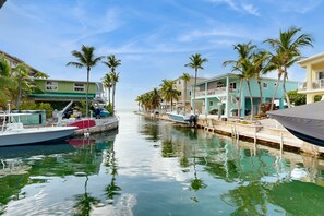 A marina with boats docked along a waterway, surrounded by buildings with balconies and palm trees. - Oceanfront, Snowbird-Friendly Home with High-Speed WiFi, Ocean Views, and Dock (Key Largo)