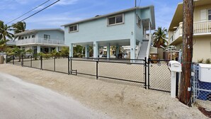 A two-story house with a covered porch, a fenced yard, and a mailbox. - Spacious canal-front home with balcony - monthly rental (Key Largo)