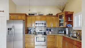 A kitchen with wooden cabinets, stainless steel appliances, granite countertops, and decorative items. - Spacious canal-front home with balcony - monthly rental (Key Largo)