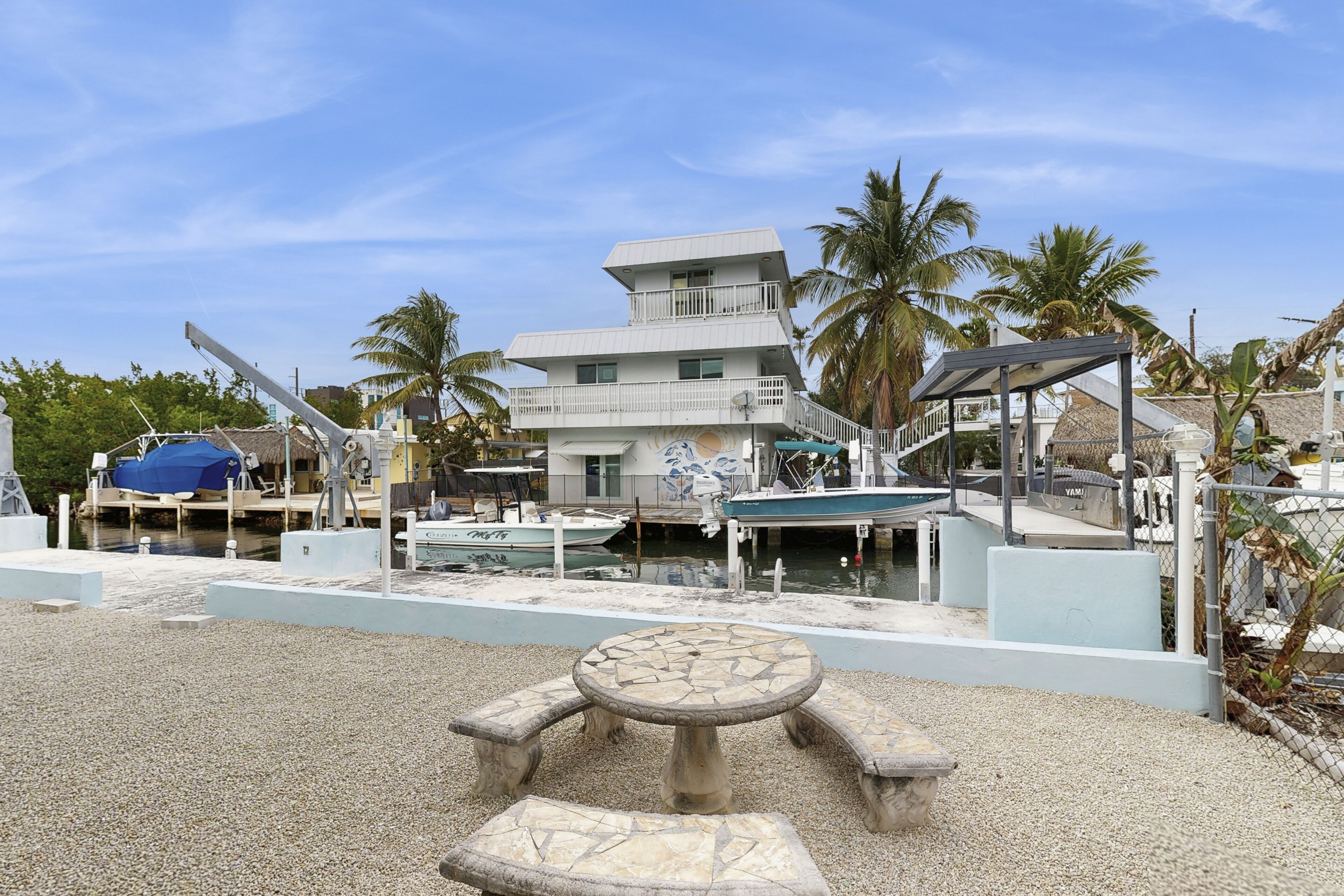 A multi-story building with a balcony, a covered outdoor seating area, and a dock with boats.