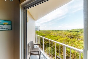 A balcony with a view of a dense green landscape, a white chair, and a sign on the wall. - Coastal retreat with private balcony, pool, & easy beach access (Tavernier)