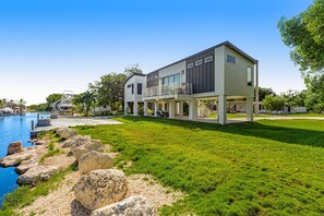 A modern two-story house with a large balcony, a swimming pool, and a well-maintained lawn. - Beautiful waterfront home with central AC, dock, lovely balcony & patio (Big Pine Key)