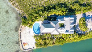 Vista aérea de un resort con piscina, playa y vegetación tropical.