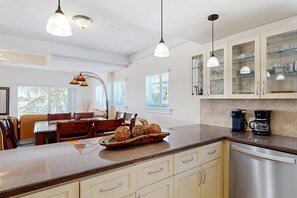 Eine moderne Küche mit Kochinsel, weißen Schränken und einem Essbereich mit Holztisch und Stühlen.