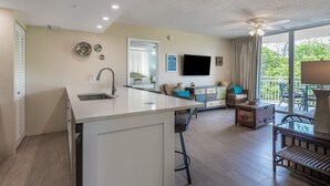 Une cuisine moderne dotée d’un îlot central, un coin repas avec une table et des chaises, et un balcon avec vue.