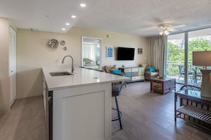 Une cuisine moderne dotée d’un îlot central, un coin repas avec une table et des chaises, et un balcon avec vue.