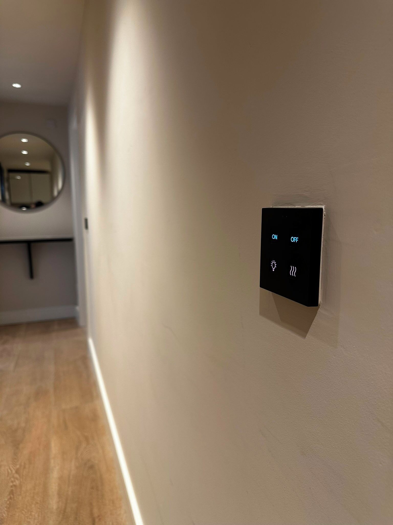 Un corridoio con un pannello di controllo a parete che include interruttori ON/OFF e simboli per luce e ventilatore.