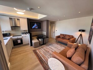 A modern living space with a kitchen, seating area, and a flat-screen TV. - Temple Bar Premium Apartments (Dublin)