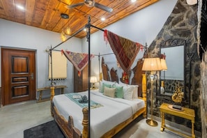 A four-poster bed with a wooden headboard, a stone wall, a mirror, and a floor lamp. - ELIVAAS Zephyr Sierra 2-BHK Hillside (Dhanaulti)