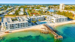 Eine Vogelperspektive auf ein Küstenhotel mit mehreren Gebäuden, einem Strand und einem Steg.