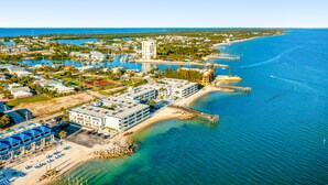 Luftaufnahme eines Küstenresorts mit mehreren Gebäuden, einer Marina und einem Strand.