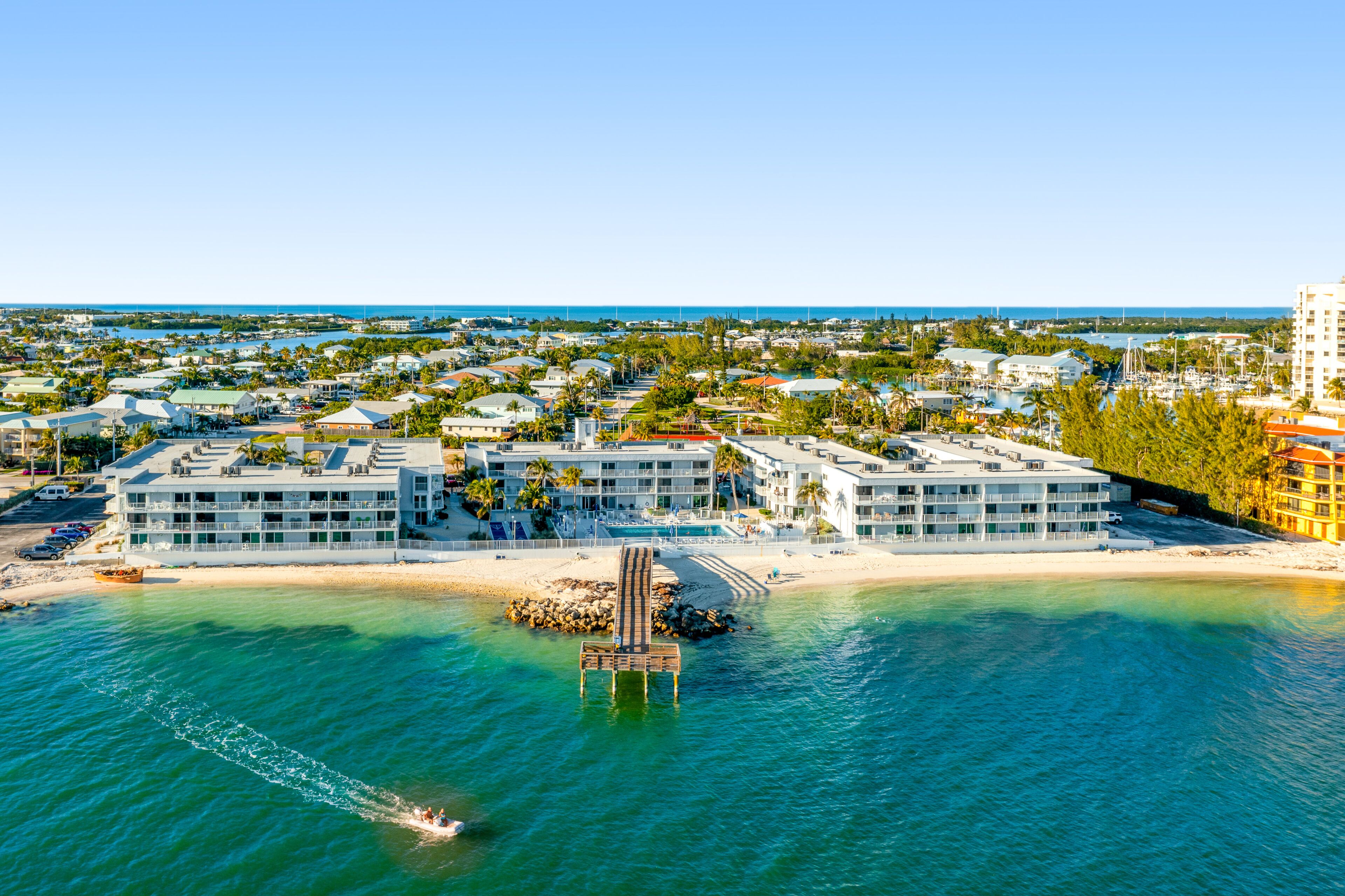A coastal resort with multiple buildings, a pier, and a beach.